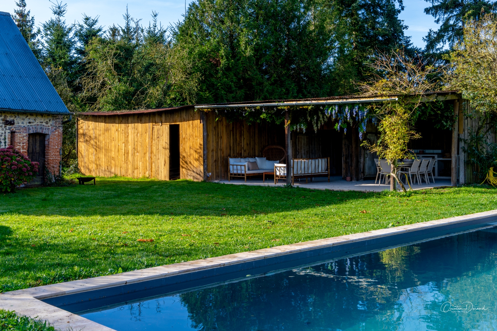 Wide view of the pool and wooden outbuilding