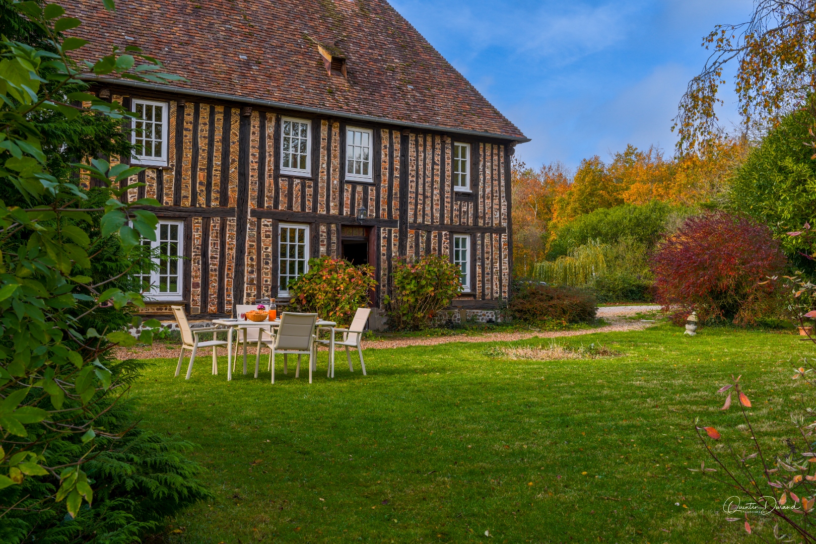 Half-timbered facade of the manor with flowering autumn garden