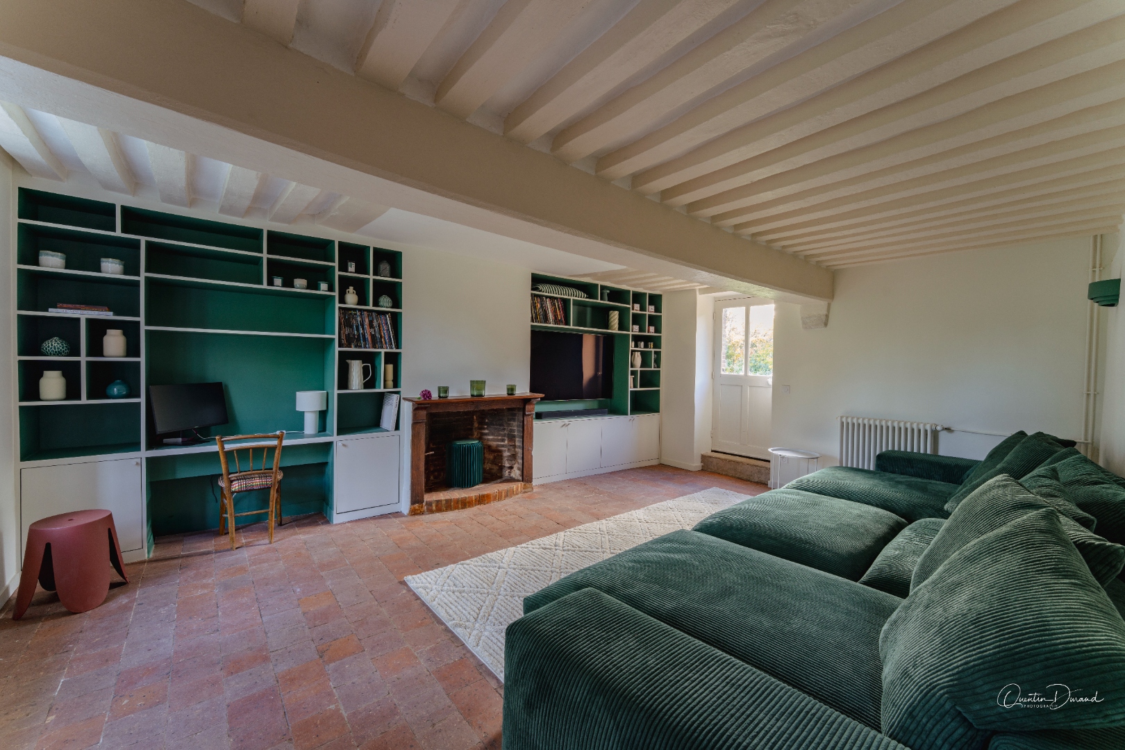 TV room with large green sofa, bookcase, and fireplace